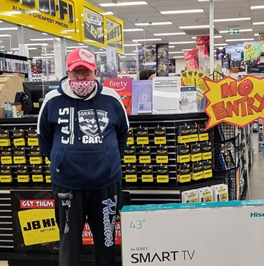 A male stands at JB Hi Fi next to a Smart TV