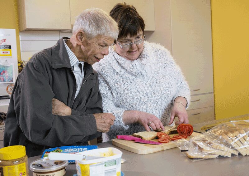 elderly man and support worker make a sandwich together during in home support services