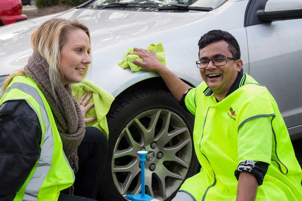 female & male supported employment workers at oc enterprises car wash wiping down a car in fluro vest uniform