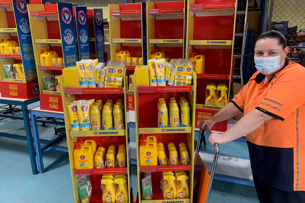 A person pushing a trolley with yellow items in a yellow display unit