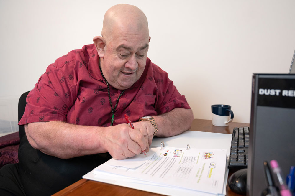 supported independent living participant sitting down at desk completing paperwork