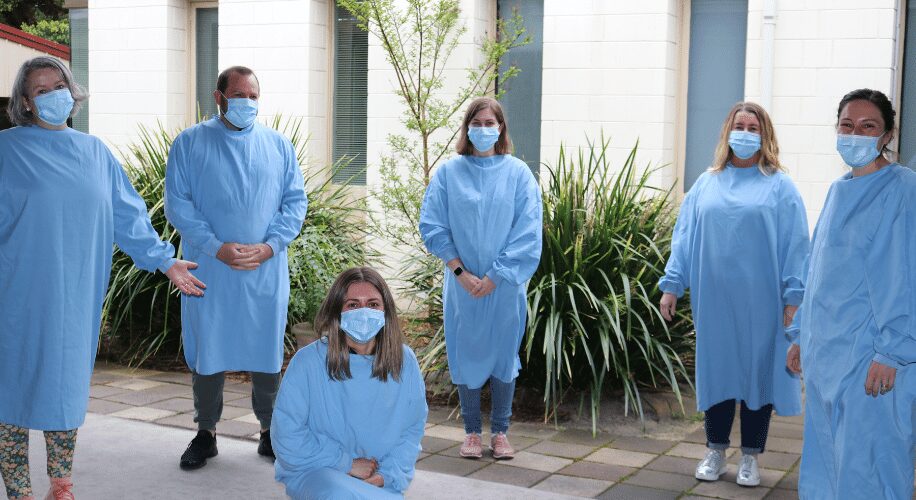 Staff from Insurance Australia Group wearing gowns and masks at OCC Enterprises during stage 4 lockdown