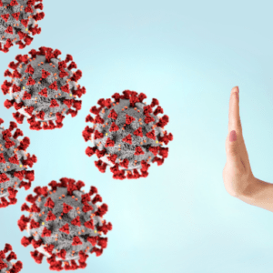 Six coronavirus particles are floating in mid air. A hand signalling a stop sign is in front of the particles.