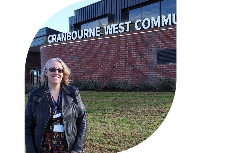 Person with sunglasses standing outside a building with sign that reads Cranbourne West Community Hub