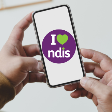Two hands holding a phone with the purple circle I heart NDIS logo