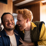 Red haired man sharing a laugh with a young man who has a disability