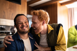 Red haired man sharing a laugh with a young man who has a disability